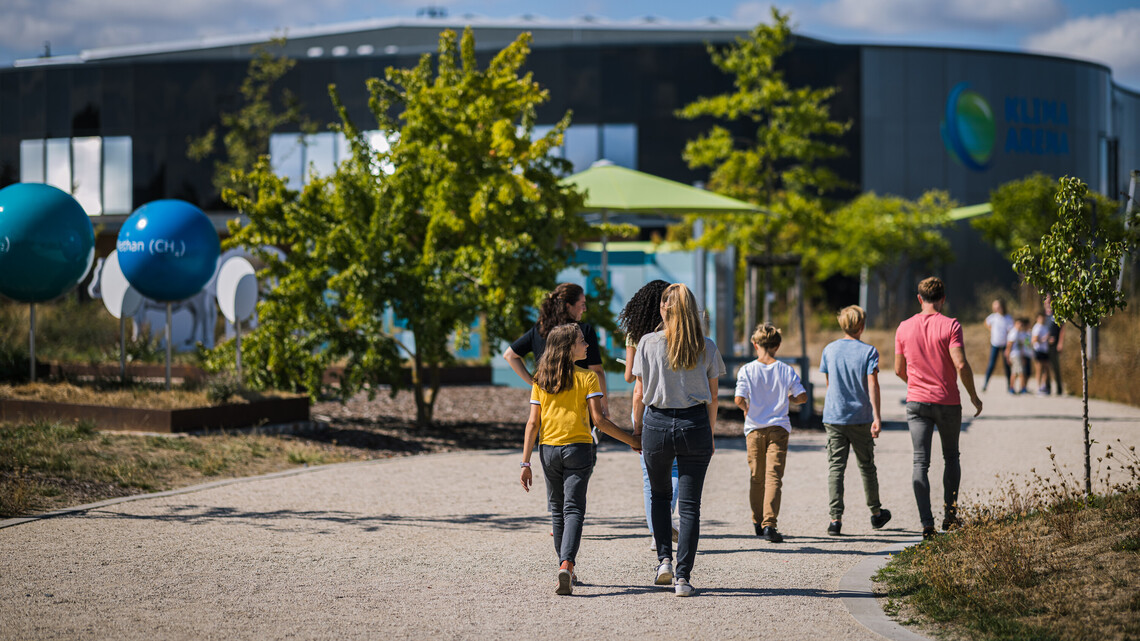 Familie l&auml;uft durch den Themenpark der Klima Arena